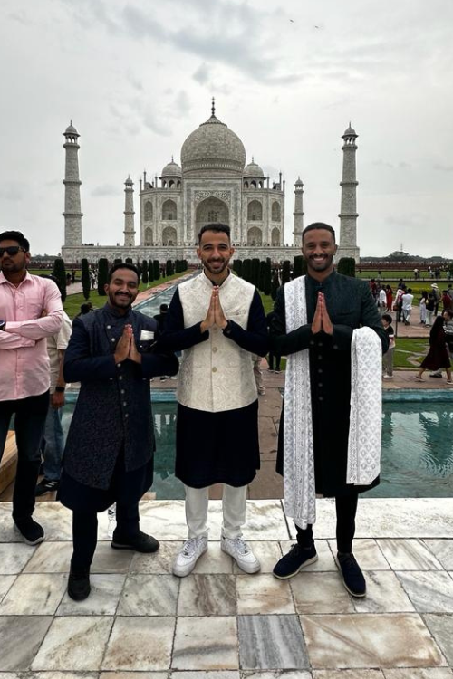 three man are join there hands as pray position, behind there taj mahal was there.